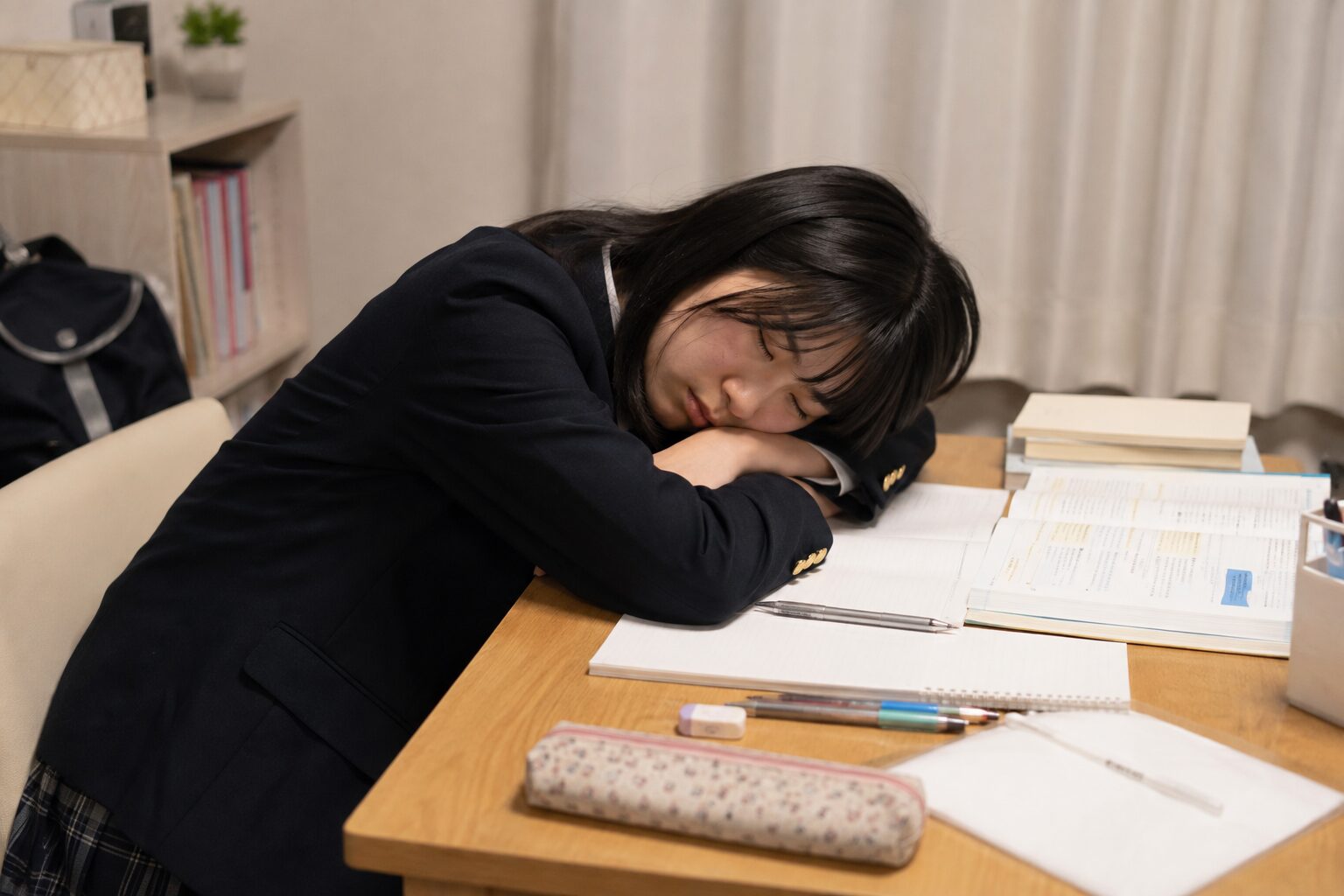 参考書やノートを広げた机で、勉強中に寝てしまった高校生